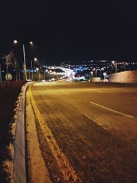 Illuminated road against sky at night