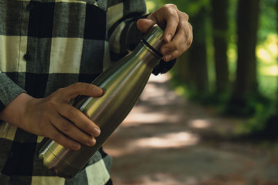 Close-up of unrecognizable female hand holding water bottle. reusable steel thermo water bottle in