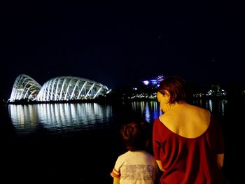 Rear view of boy with illuminated water at night