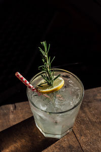 Rosemary lemonade soda cocktail with ice and gingham drinking straw on whiskey barrel happy hour