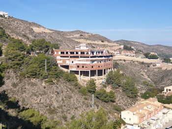 Residential buildings by mountain against sky