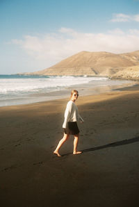 Full length of woman standing on beach against sky