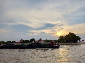 Boats moored in river against sky during sunset