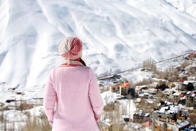 Rear view of woman looking at city against snow capped mountain