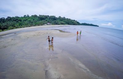 People walking on beach against sky