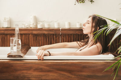 A girl with long hair lies and relaxes in a wooden bath
