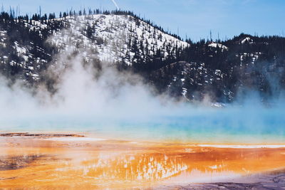 Grand prismatic spring by snow covered mountains at yellowstone national park