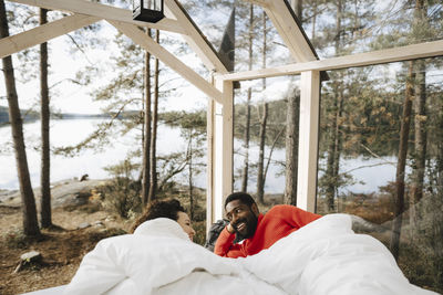 Happy couple talking while lying in cottage during weekend