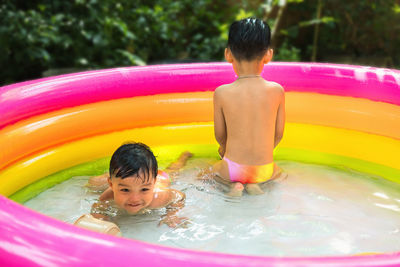 Siblings playing in wading pool