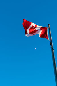 Low angle view of flags flag against clear blue sky