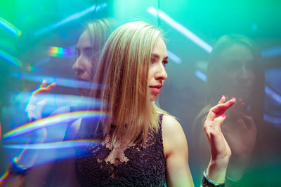 Woman looking away against illuminated wall