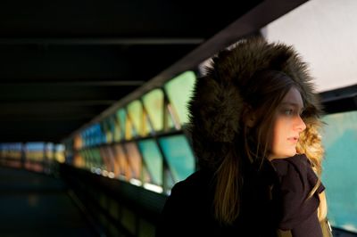 Close-up of woman wearing fur coat looking through window