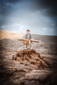 Man sitting on rock at beach against sky