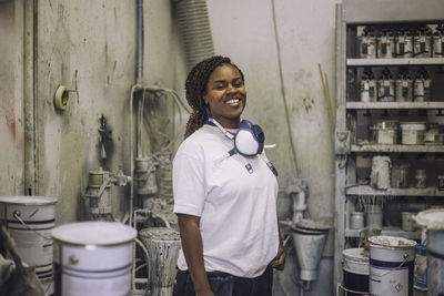 Portrait of smiling female painter standing in workshop