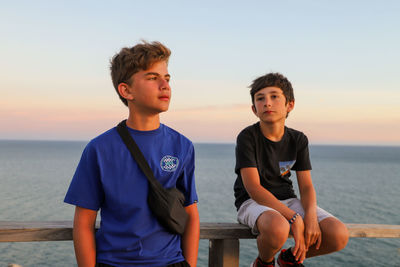 Portrait of boy at sea against sky during sunset