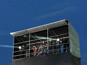 Low angle view of people against clear blue sky