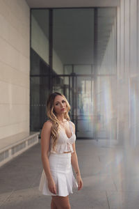 Young woman standing against wall in city