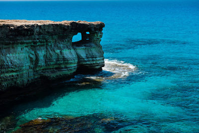 Rock formation on beach against blue sky