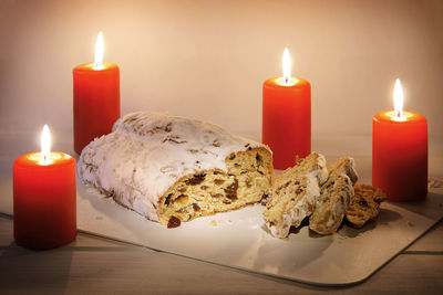 Stollen amidst candles in plate on table