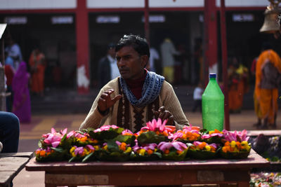 Woman standing by flowers for sale at market stall