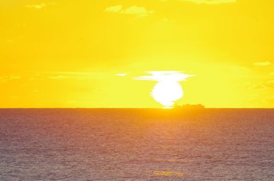 Airplane flying over sea against sky during sunset