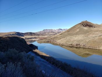 Scenic view of lake and mountains against clear blue sky