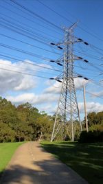 Electricity pylon on field against cloudy sky