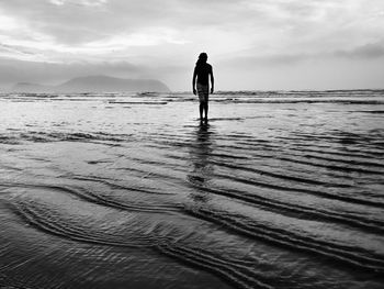 Silhouette man standing on beach against sky