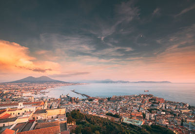 High angle view of townscape by sea against sky during sunset