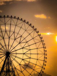 Low angle view of ferris wheel against sky during sunset