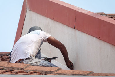 Low angle view of man relaxing against wall