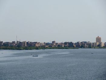 Sea by buildings against clear sky