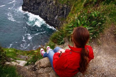 Rear view of woman standing on rock by waterfall