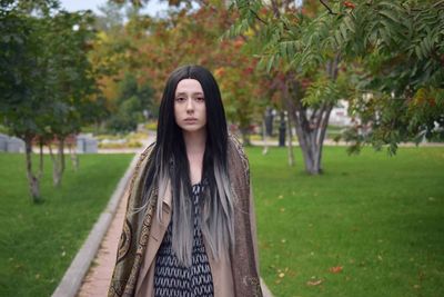 Portrait of young woman standing in park