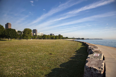 Scenic view of grassy field and sea against sky