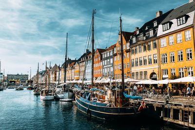 Sailboats moored on canal by buildings in city