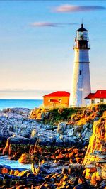 Lighthouse by sea against sky