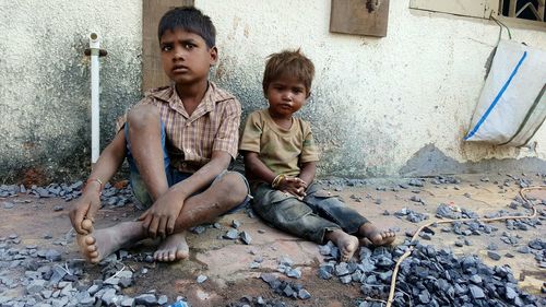Portrait of boy sitting with brother on footpath