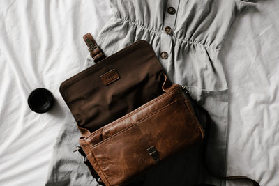 Directly above shot of leather bag and dress on sheet