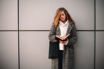 Portrait of a beautiful young woman standing against wall