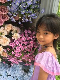 Portrait of cute girl standing by pink flowering plants