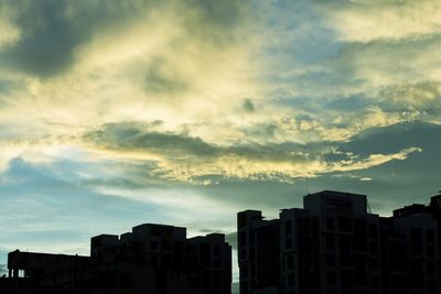Low angle view of buildings against cloudy sky