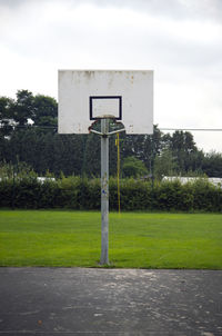 Basketball hoop on field against sky