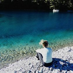 Rear view of woman sitting by sea