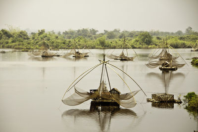 Chinese fishing nets in lake against sky