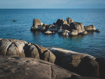 Rocks by sea against blue sky