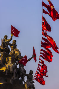Low angle view of flag statue against clear sky
