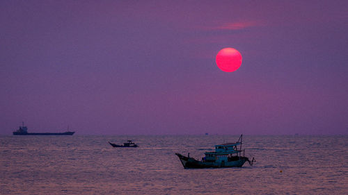 Boat sailing in sea against sky during sunset