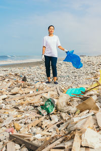 Young woman volunteer on beach full of garbage