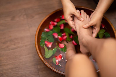 High angle view of woman hand on red rose